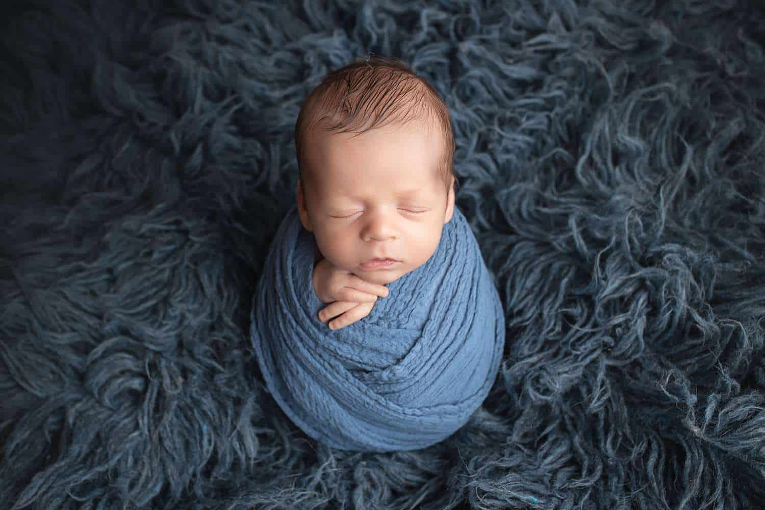 newborn photographer in rochester ny captures newborn baby boy asleep in a blue fur