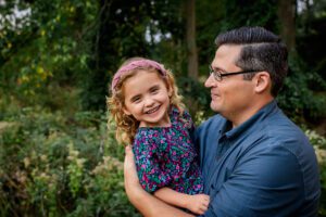 family photographer in rochester ny captures little girl smiling with her dad during fall mini session