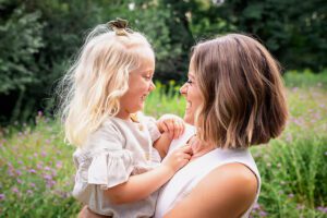 family photographer in rochester ny captures mom and daughter playing in the flowers