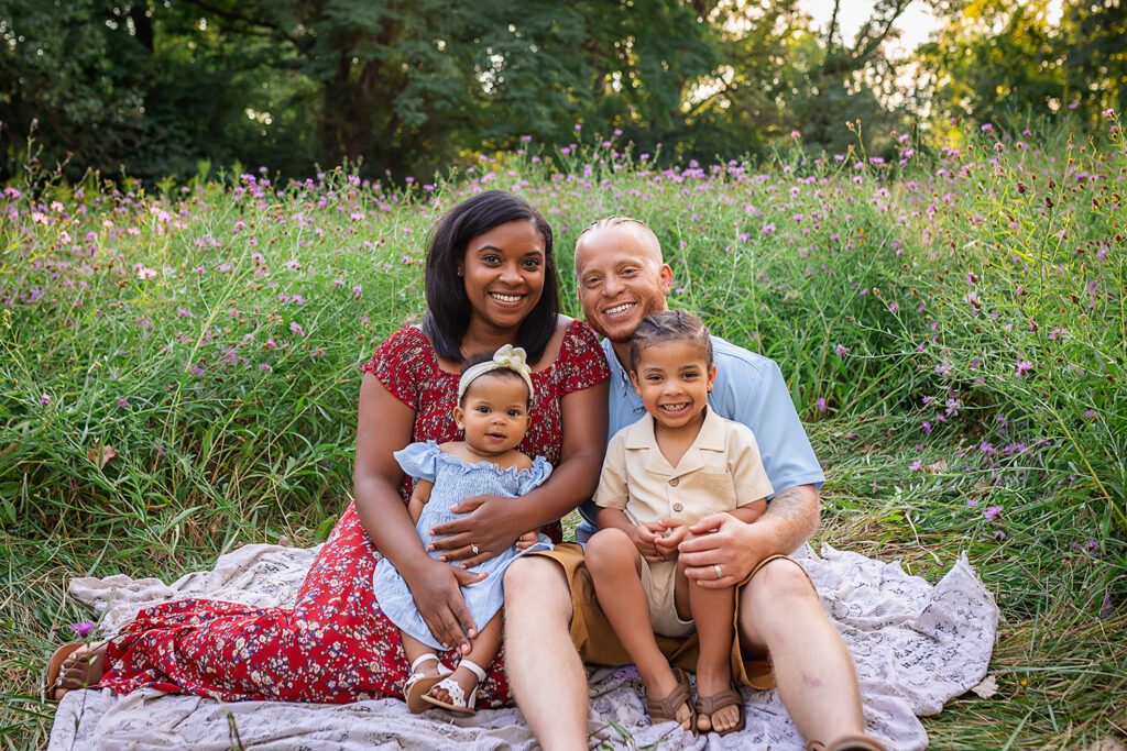 family photographer in rochester ny captures family sitting together in the flowers