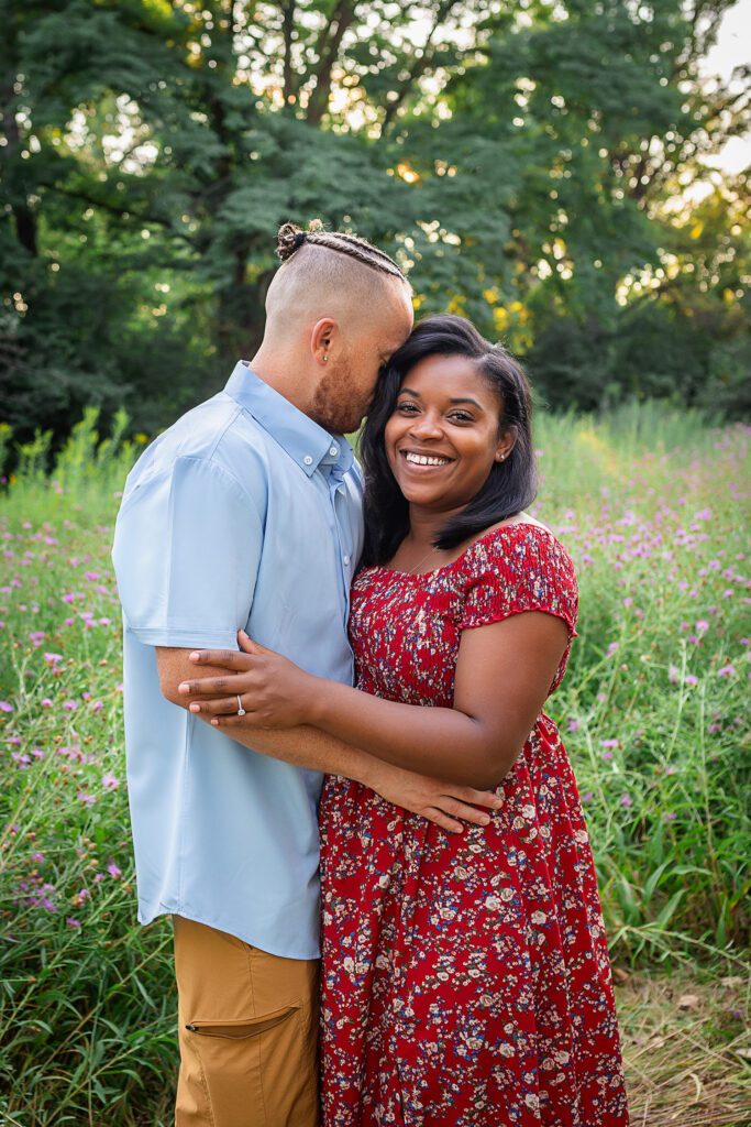 family photographer in rochester ny captures mom and dad snuggling together in the flowers