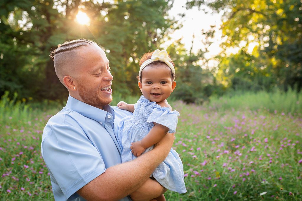 family photographer in rochester ny captures dad and daughter snuggling together in the flowers
