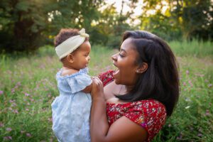 family photographer in rochester ny captures mom and daughter snuggling together in the flowers