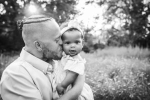 family photographer in rochester ny captures dad and daughter snuggling together in the flowers