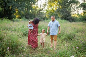 family photographer in rochester ny captures family walking together in the flowers