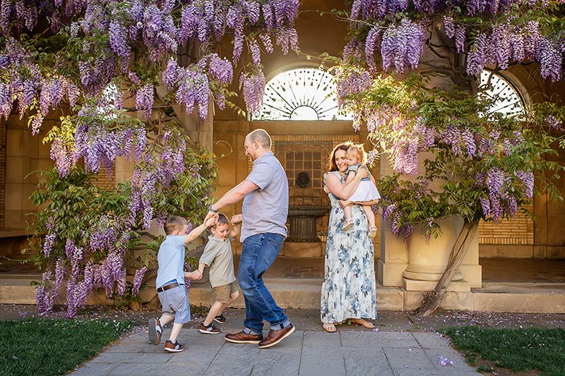 rochester ny family photographer captures family playing together under the wisteria at the George Eastman Museum